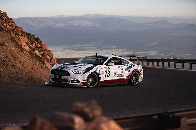 Mustang driving uphill with landscape in background
